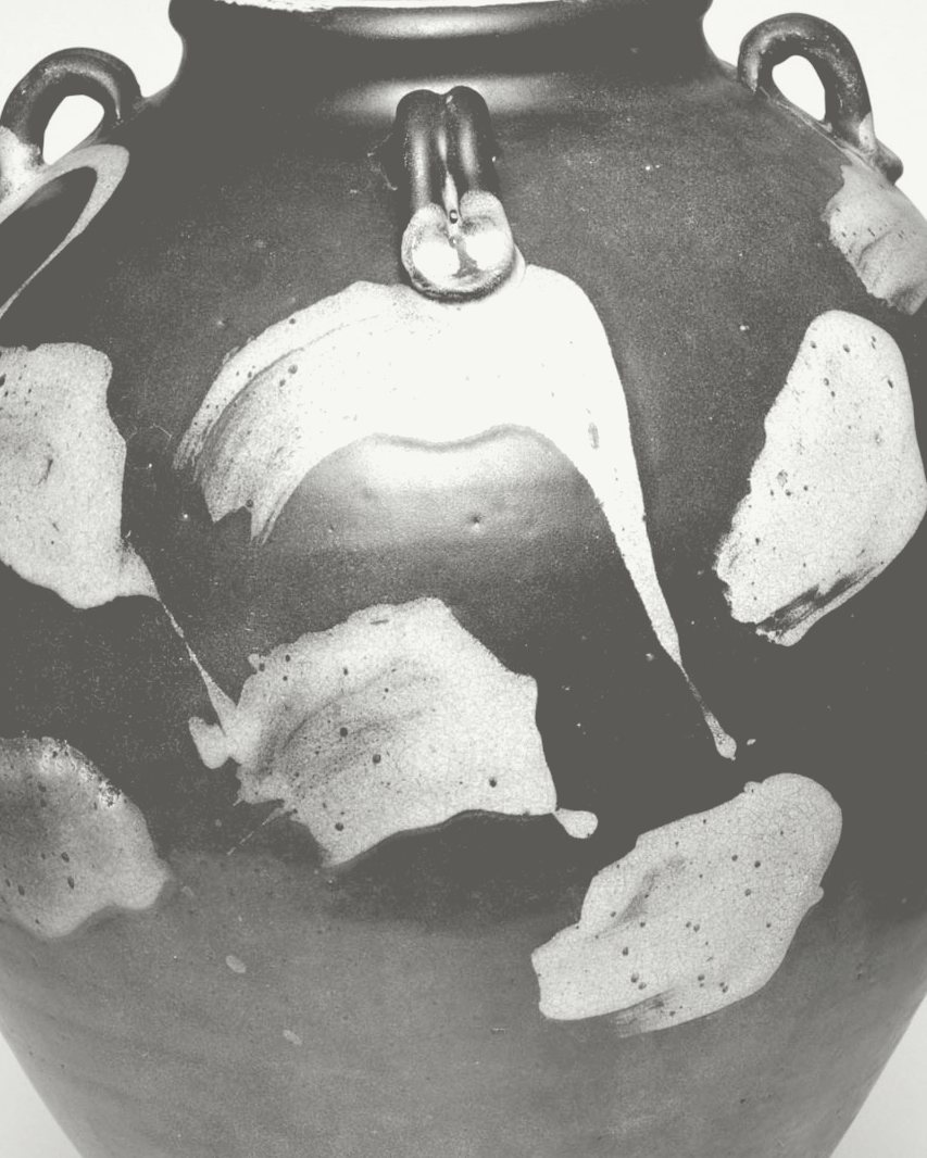 Detail: pale glaze splashes and a lug on the dark body