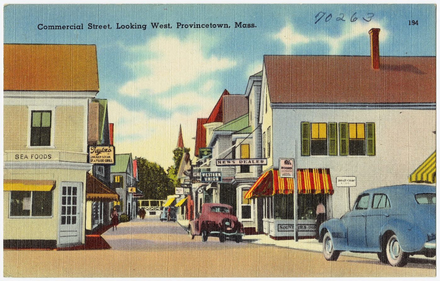 Postcard: Commercial Street with shopfronts, striped awnings and parked cars.